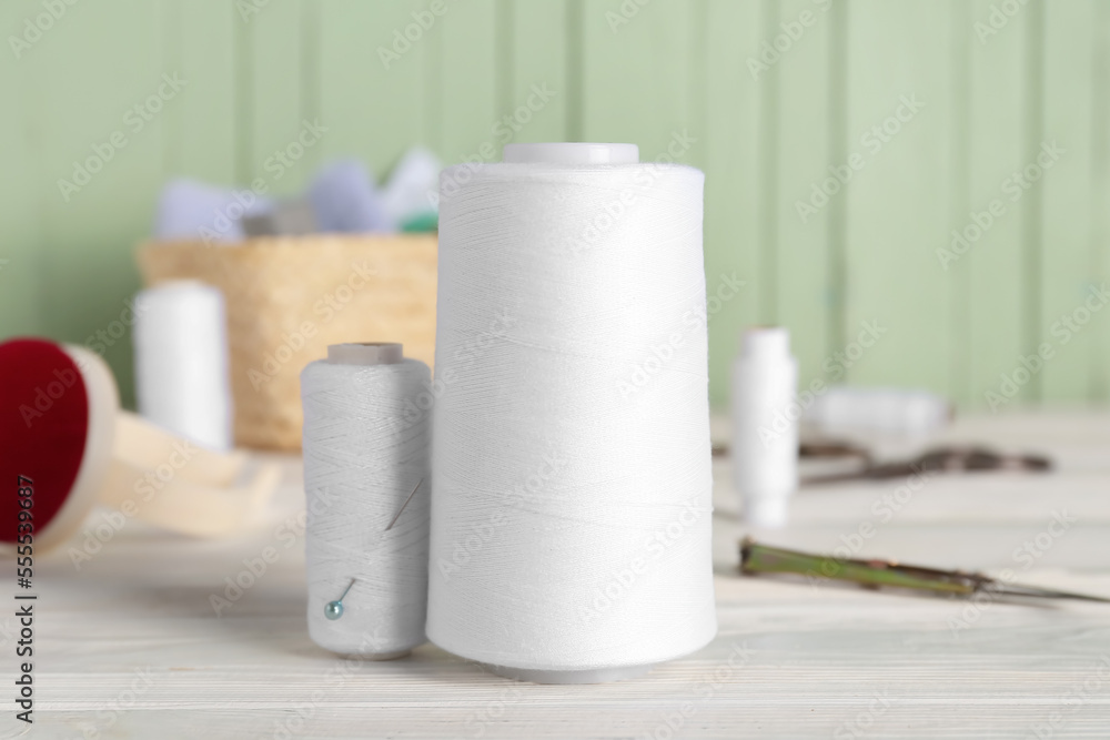 Naklejka premium White thread spools on light wooden table