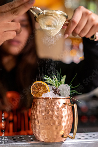 Photography Making a moscow mule cocktail in a copper mug in a bar at night by a bartender,