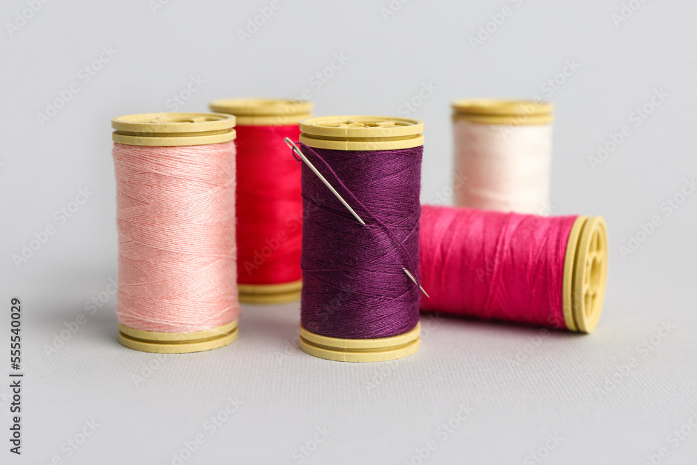 Thread spools with needle on grey background Thread spools with needle on grey background