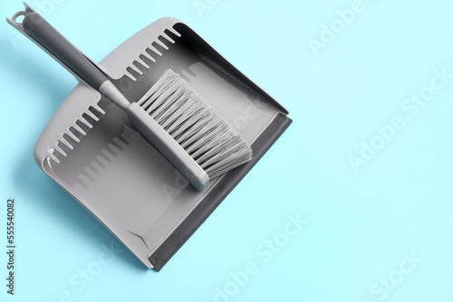 Dustpan and brush on color background