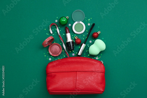 Composition with bag, cosmetics and Christmas decor on green background