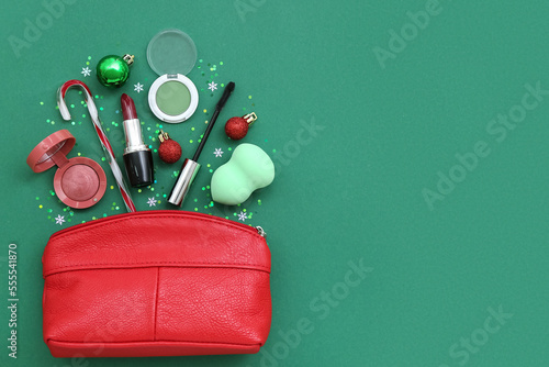 Composition with bag, cosmetics and Christmas decor on green background