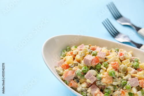 Bowl of tasty Olivier salad on color background, closeup