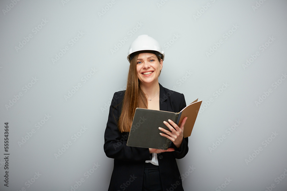 Woman in black suit and safety helmet holding open book. Woman in black suit and safety helmet holding open book.