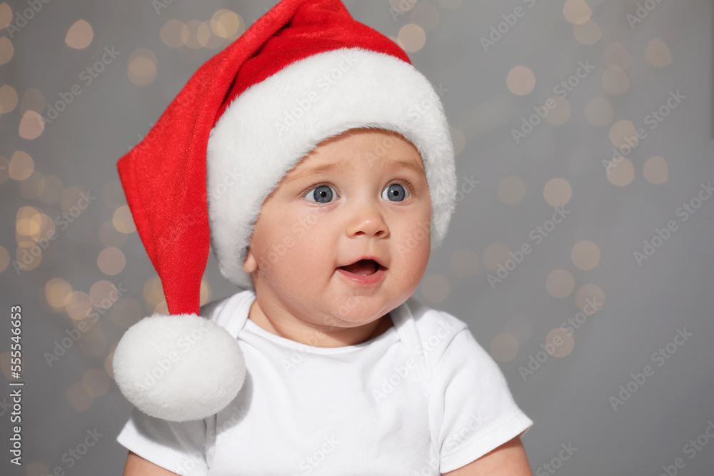 Cute baby in Santa hat against blurred lights. Christmas celebration Cute baby in Santa hat against blurred lights. Christmas celebration