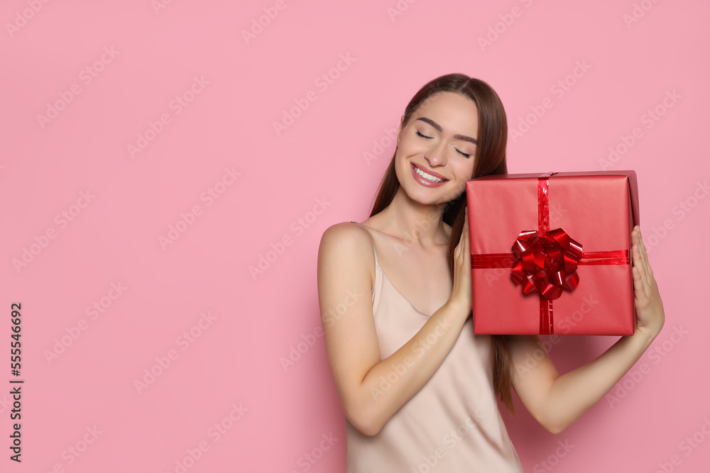 Portrait of happy young woman with gift box on pink background. Space for text Portrait of happy young woman with gift box on pink background. Space for text