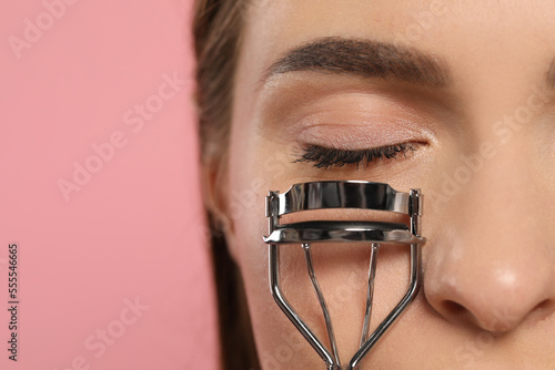 Obraz na plátně Woman with eyelash curler on pink background, closeup