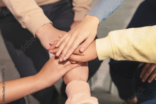 Group of people holding hands together indoors  closeup. Unity concept