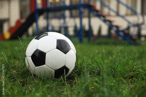 Wet leather soccer ball on grass outdoors, space for text