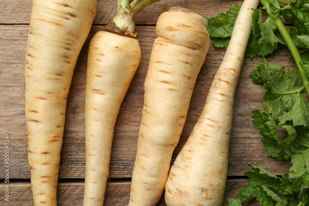 Fresh ripe parsnips with leaves on wooden table, flat lay Fresh ripe parsnips with leaves on wooden table, flat lay