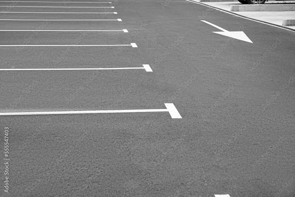 White painted car parking lots and arrow marking on asphalt outdoors