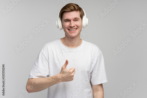 Positive man wearing headset listening to music and showing cool gesture