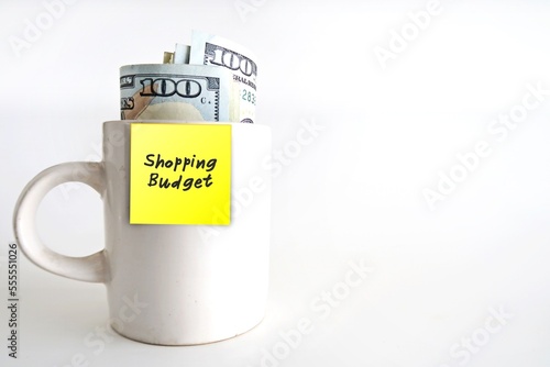 Wallpaper Mural White ceramic cup, cash dollars money with yellow paper sticky note written SHOPPING BUDGET, isolated on white background. Concept of setting limited budget for shopping spending, money management Torontodigital.ca