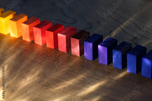 Colored wooden blocks aligned on an old vintage wooden table with incoming light rays. bold colors in the dark. photo