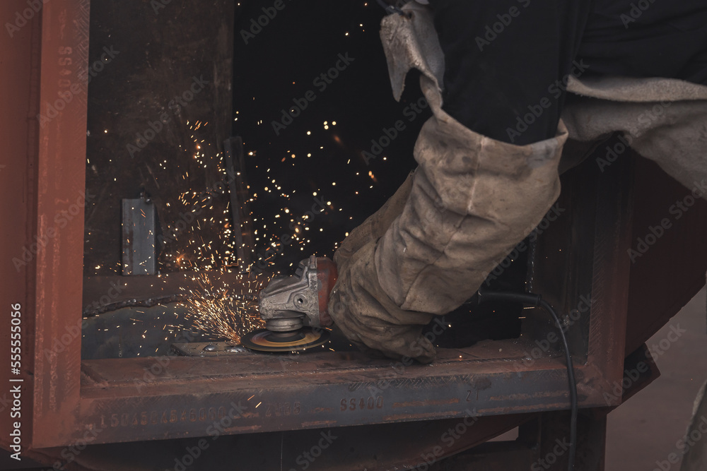 electric grinding wheel on steel structure in factory ,Grinding the seams of an iron frame - bright sparkles comes off the metal in the process electric grinding wheel on steel structure in factory ,Grinding the seams of an iron frame - bright sparkles comes off the metal in the process