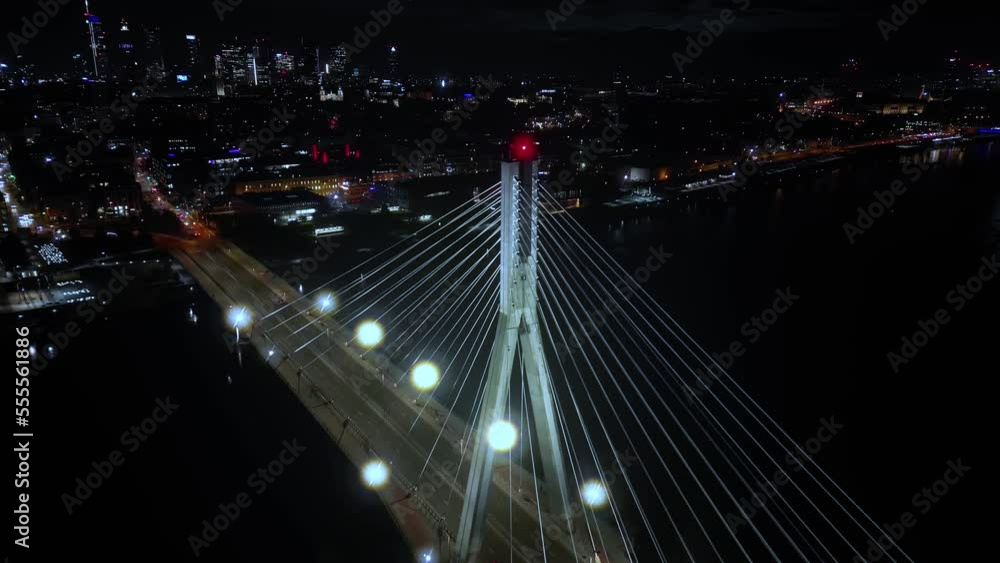 Aerial panoramic shot of Warsaw cityscape. Swietokrzyski suspension bridge over Vistula river, skyscrapers downtown urban skyline at night. Cinematic city panorama flyover cable bridge towers Aerial panoramic shot of Warsaw cityscape. Swietokrzyski suspension bridge over Vistula river, skyscrapers downtown urban skyline at night. Cinematic city panorama flyover cable bridge towers