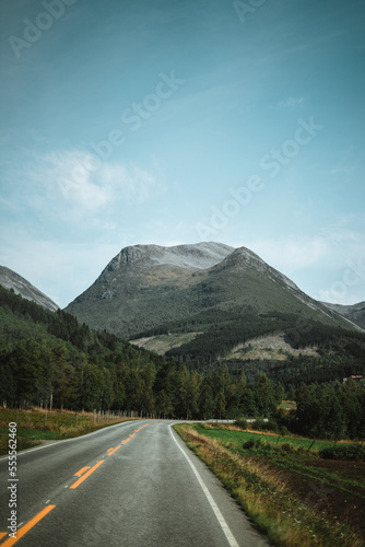 Empty road leading to the mountains on a moody day in Norway with clouds.