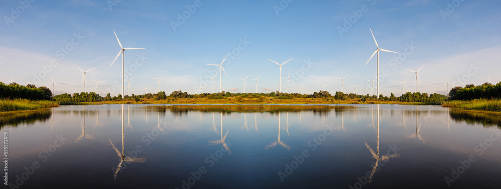 Powerful Wind turbine farm for pure energy production on Beautiful clear blue sky with white clouds and wind turbine farm reflection on lake. renewable energy Powerful Wind turbine farm for pure energy production on Beautiful clear blue sky with white clouds and wind turbine farm reflection on lake. renewable energy