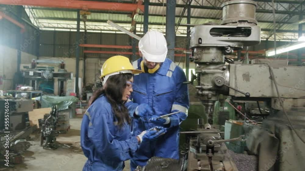 Two industrial workers in protective and safety uniforms and hardhats, male manager, and Black colleague work with metalwork machines in manufacturing factory. Professional production engineer team. Two industrial workers in protective and safety uniforms and hardhats, male manager, and Black colleague work with metalwork machines in manufacturing factory. Professional production engineer team.