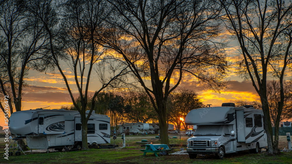 Campers at campsite in winter at sunset with no leaves on the trees - obrazy, fototapety, plakaty 