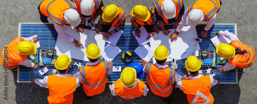 Fotografie Team young man and woman architects and engineer working on solar panel and his blueprints with Solar photovoltaic equipment on factory construction site