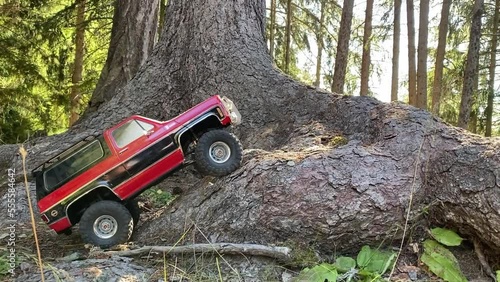 A remote controlled crawler drives over a tree root in the forest. RC Car photo