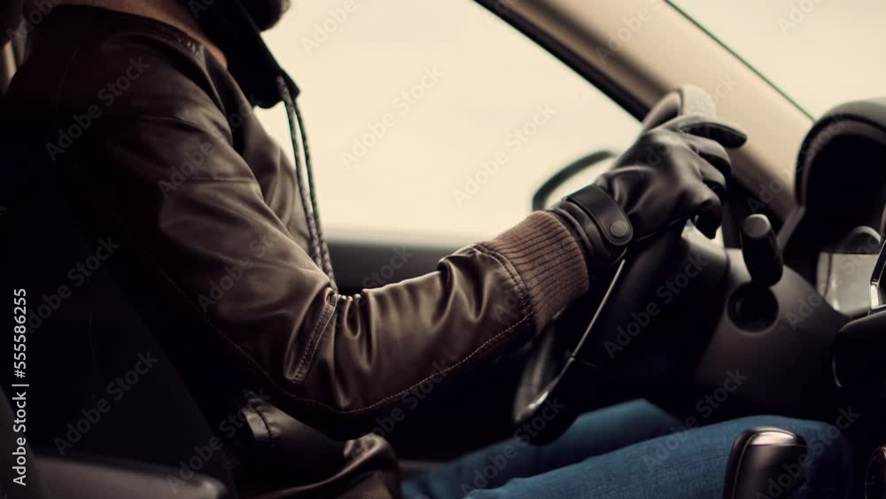 A taxi driver wearing a leather jacket and gloves is driving his car ...