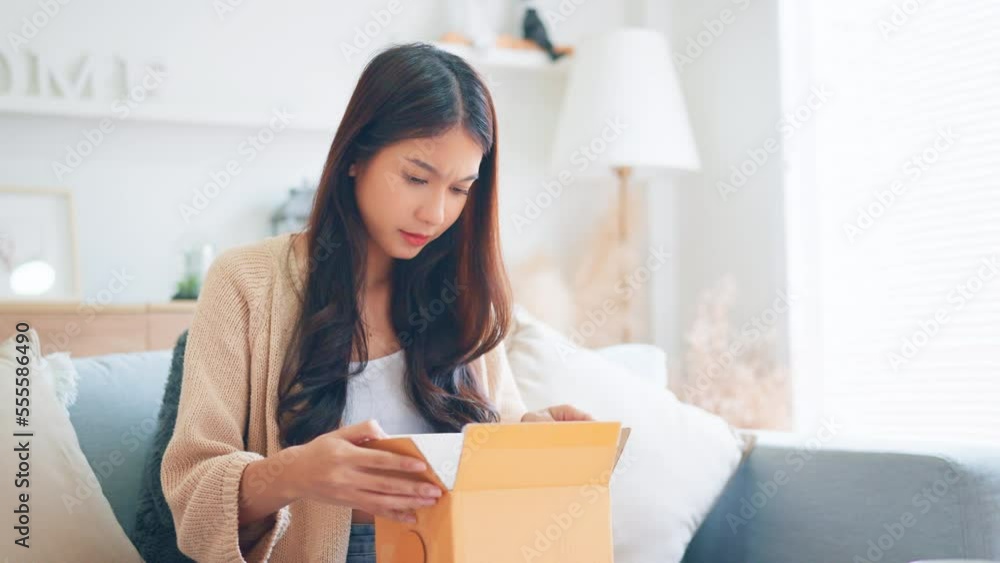 Wrong Item. Bad delivery service, Upset young asian woman unpacking cardboard box on sofa at home, receiving damaged item, Female feeling sad after unpacking box with delivery. Wrong Item. Bad delivery service, Upset young asian woman unpacking cardboard box on sofa at home, receiving damaged item, Female feeling sad after unpacking box with delivery.