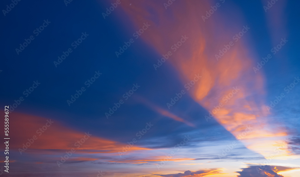 Dramatic dusk sky background in the evening with majestic orange sunlight on dark blue clouds after sundown
