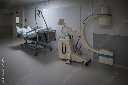 in a hospital corridor there is an empty bed and an x-ray machine