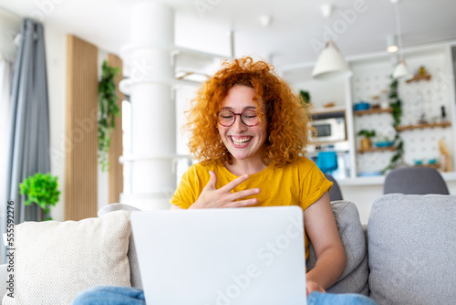 Happy young woman having fun doing video call using laptop in her home, waving hand video conference calling on laptop computer sit on sofa distance learn zoom online virtual meeting at home Fototapeta