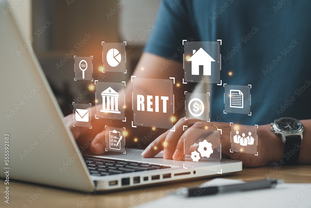 Naklejka premium Businessmen using a computer to Real Estate Investment Trust REIT on double exsposure business background..