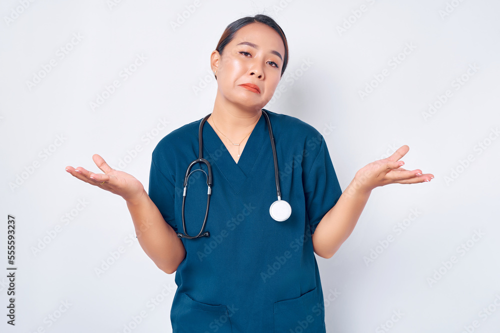 Clueless young Asian woman nurse wearing blue uniform with a stethoscope shrugging and spread hands sideways unaware, dont now, cant help isolated on white background. Healthcare medicine concept Clueless young Asian woman nurse wearing blue uniform with a stethoscope shrugging and spread hands sideways unaware, dont now, cant help isolated on white background. Healthcare medicine concept