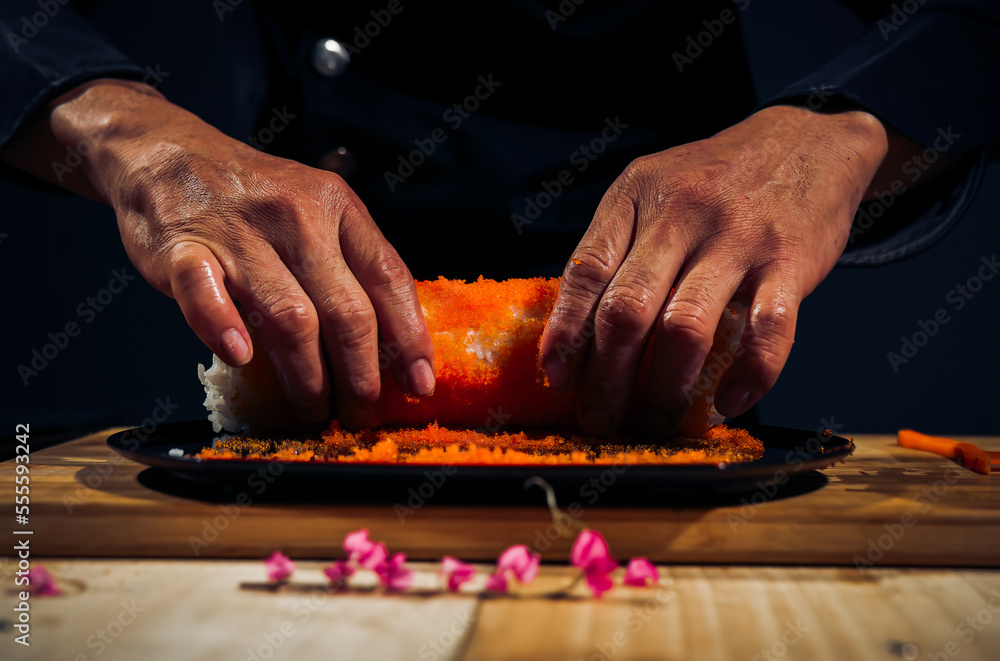 Japanese chef making California Maki Sushi with Masago - Roll made of Crab Meat, Avocado, Cucumber inside. Masago (smelt roe) outside with tuna, salmon, shrimp,traditional Japanese food ,Dark Tone Japanese chef making California Maki Sushi with Masago - Roll made of Crab Meat, Avocado, Cucumber inside. Masago (smelt roe) outside with tuna, salmon, shrimp,traditional Japanese food ,Dark Tone