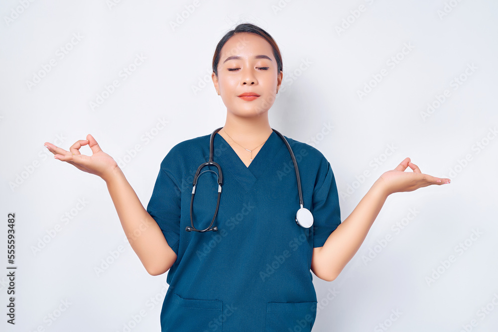calm and patient young Asian woman nurse wearing blue uniform with stethoscope staying relaxed, meditating with eyes closed isolated on white background. Healthcare medicine concept calm and patient young Asian woman nurse wearing blue uniform with stethoscope staying relaxed, meditating with eyes closed isolated on white background. Healthcare medicine concept