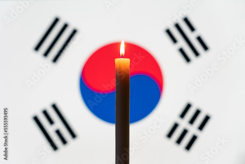 Mourning in the country. burning candle on the background of the south korea flag. Victims of cataclysm or war concept. memorial day, remembrance day. National mourning.