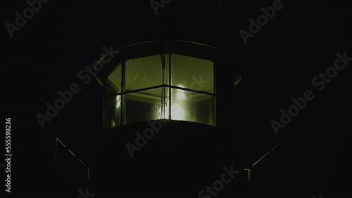 Lighthouse burning at dusk. Lighthouse light in rainy weather. Rotating lighthouse.
