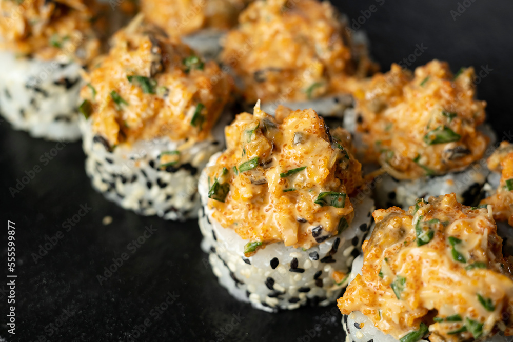 A set of fresh sushi rolls with salmon, avocado, mussels and black sesame seeds served on a black stone slate. Japanese sushi uramaki A set of fresh sushi rolls with salmon, avocado, mussels and black sesame seeds served on a black stone slate. Japanese sushi uramaki