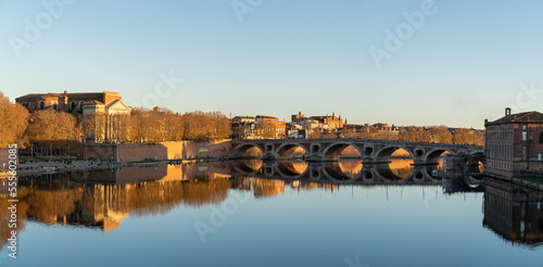 Scenic panoramic landscape of the Garonne river and landmark Pont Neuf or New Bridge at sunset in the pink city of Toulouse, France