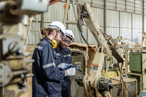 A team of male and female engineers meeting to inspect computer-controlled steel welding robots. Plan for rehearsals and installation for use.