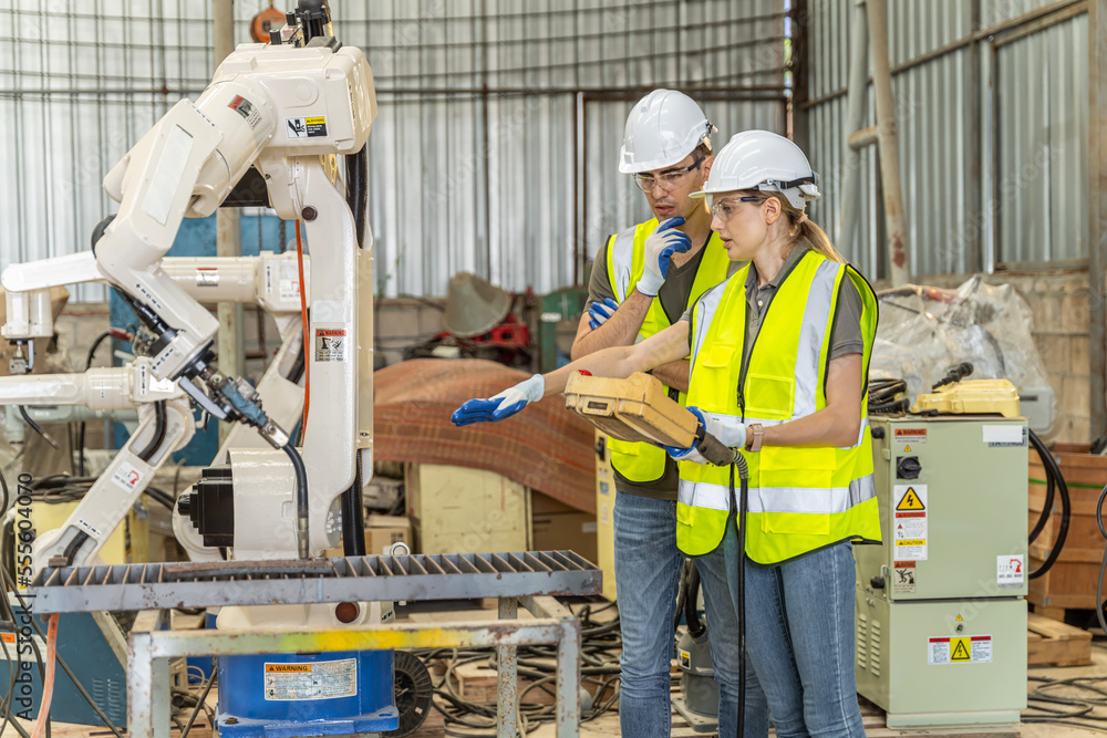 A team of male and female engineers meeting to inspect computer-controlled steel welding robots. Plan for rehearsals and installation for use. A team of male and female engineers meeting to inspect computer-controlled steel welding robots. Plan for rehearsals and installation for use.