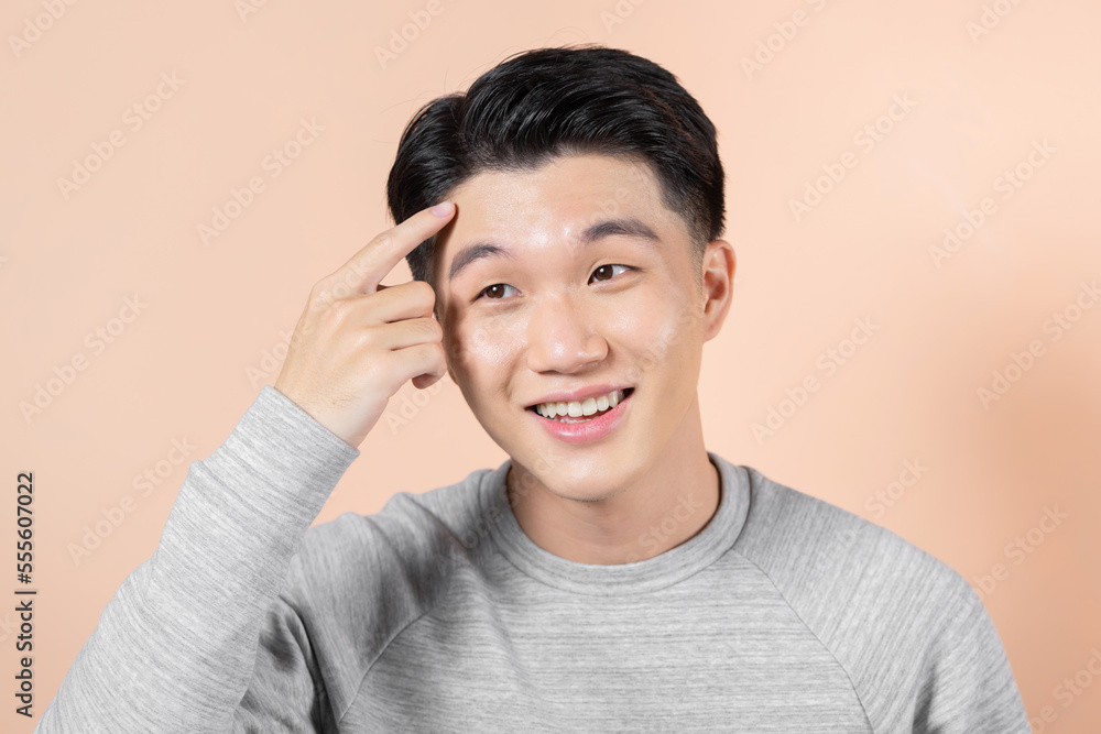 Young asian man pointing unhappy to pimple on forehead, Young asian man pointing unhappy to pimple on forehead,