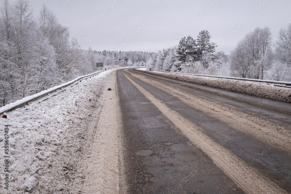 clean wet asphalt road in wintertime. Dirty snow on road sides. Long far perspective. Latvia landscape near Jelgava town. Bypass road clean wet asphalt road in wintertime. Dirty snow on road sides. Long far perspective. Latvia landscape near Jelgava town. Bypass road