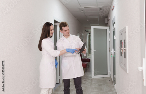 doctors discuss the medical report in the hospital. A young female doctor and a male doctor check the patient's clinical report online. Medical staff standing in the corridor of a private clinic