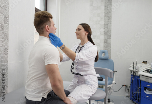 a young female doctor examines the lymph nodes of a male patient in a modern clinic