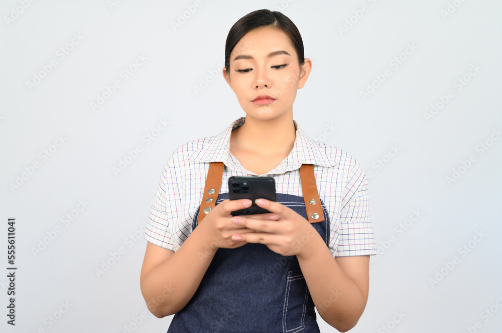 Portrait of young asian woman in waitress uniform pose with smartphone Portrait of young asian woman in waitress uniform pose with smartphone