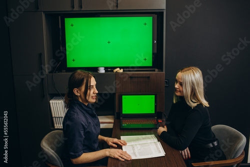 Assistant using horizontal green screen on computer while dentist preparing equipment for oral care examination in dental cabinet. Man looking at chroma key and mockup template on monitor