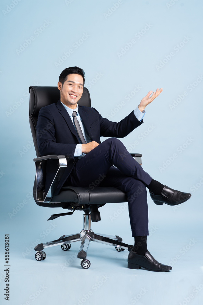 Asian businessman male portrait sitting on chair and isolated on blue background Asian businessman male portrait sitting on chair and isolated on blue background