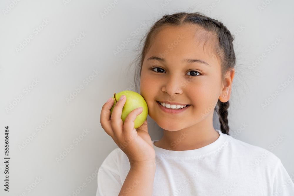 Portrait of smiling asian girl holding fresh apple and looking at camera near wall Portrait of smiling asian girl holding fresh apple and looking at camera near wall