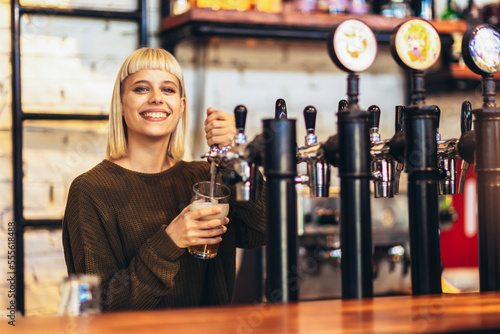Tableau sur toile Female bartender tapping beer in bar.